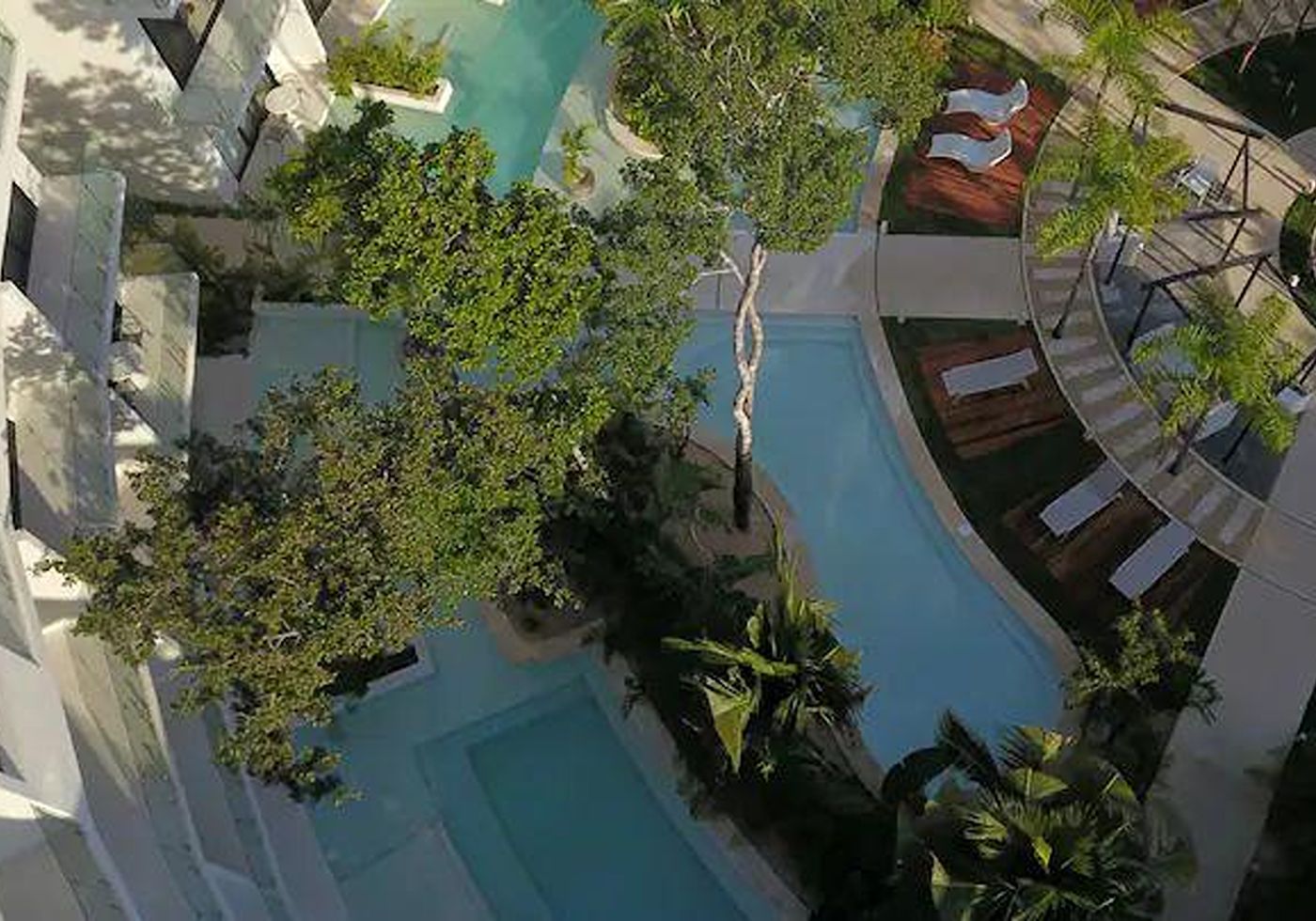 Pool and lounge chairs in front of Central Park Lagunas’s curved balconies