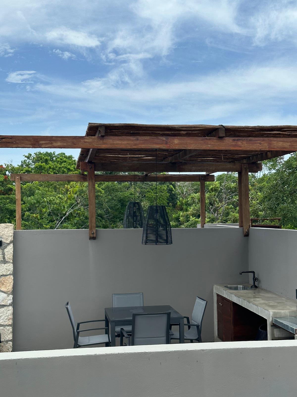 Rooftop dining area under a palapa-style pergola on B2-101’s private roof level