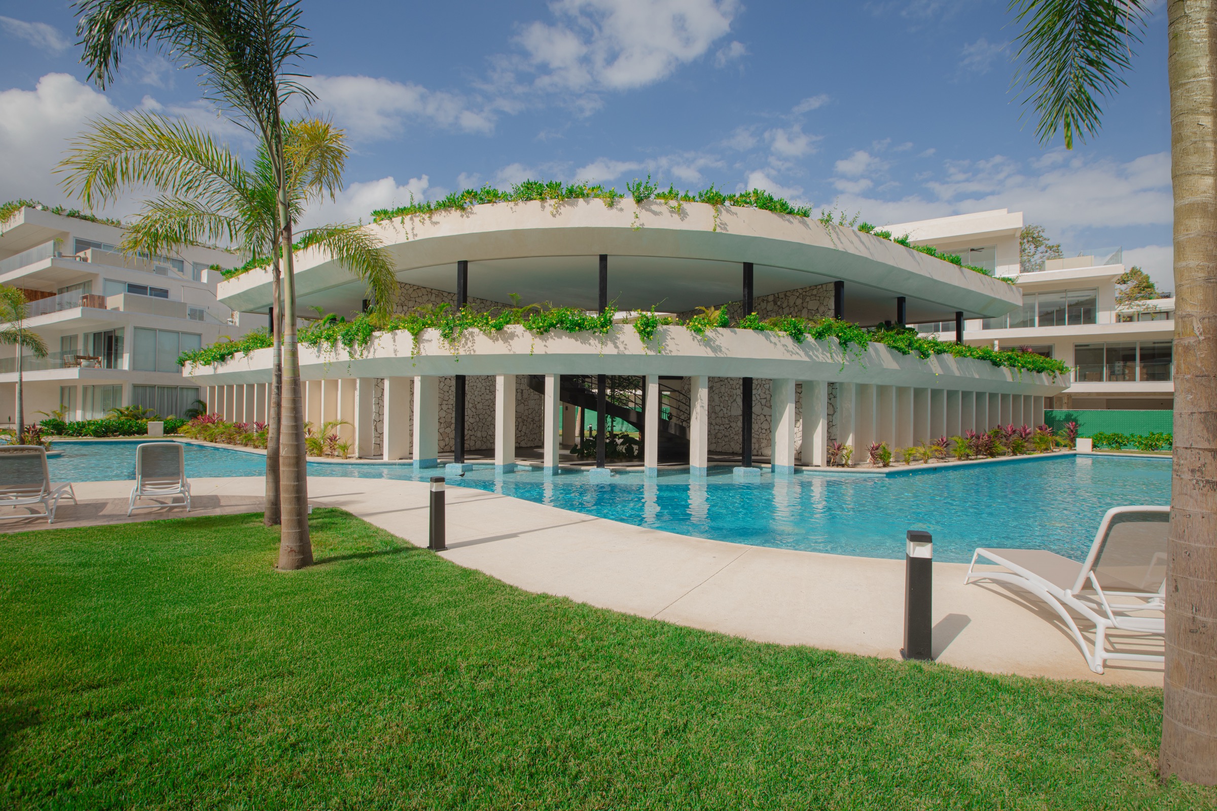 Clubhouse at The Leaf Condos Playacar seen from the lawn across the pool