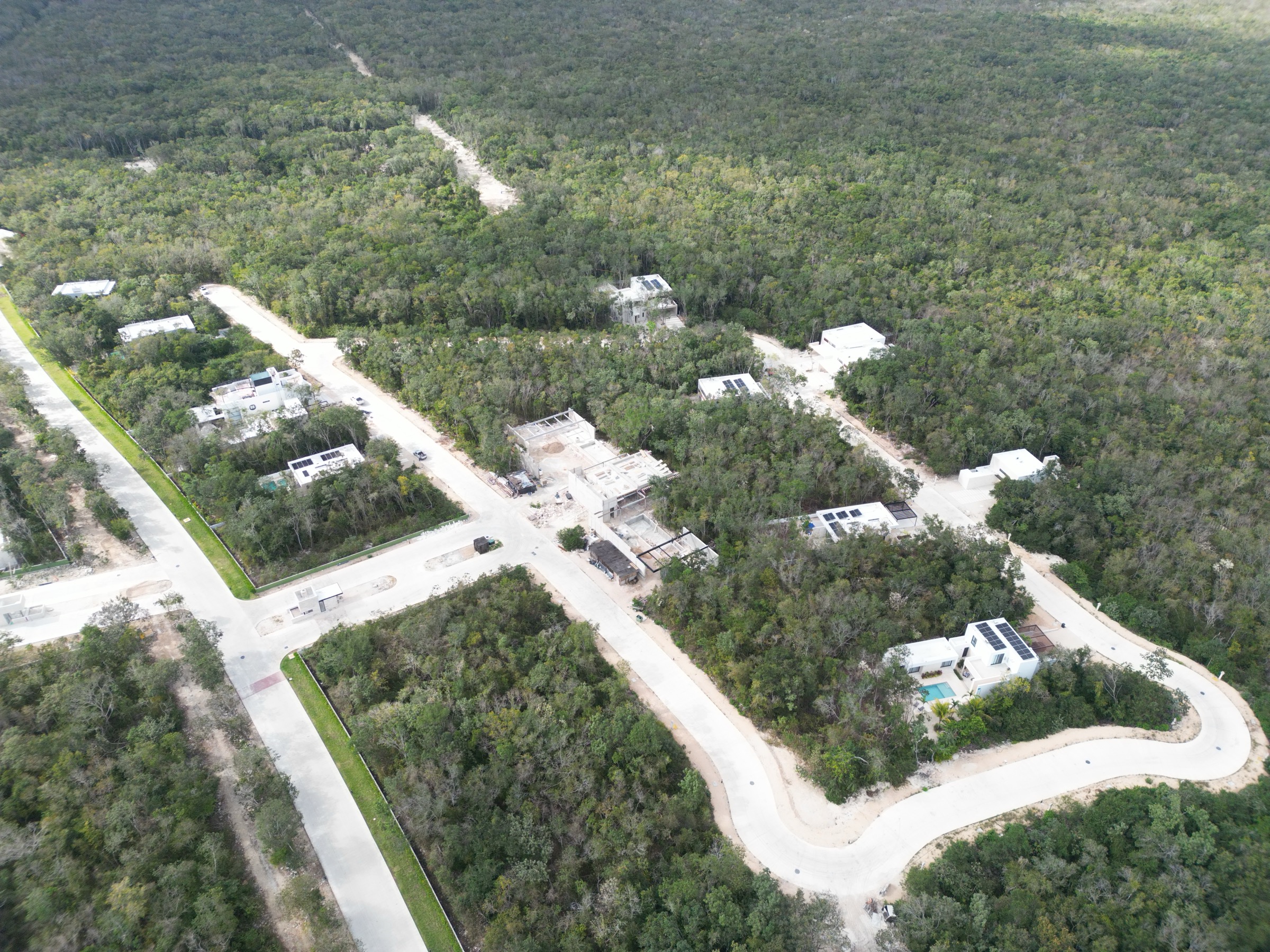 Aerial photograph of finished houses with private pools built by individual lot owners among the trees