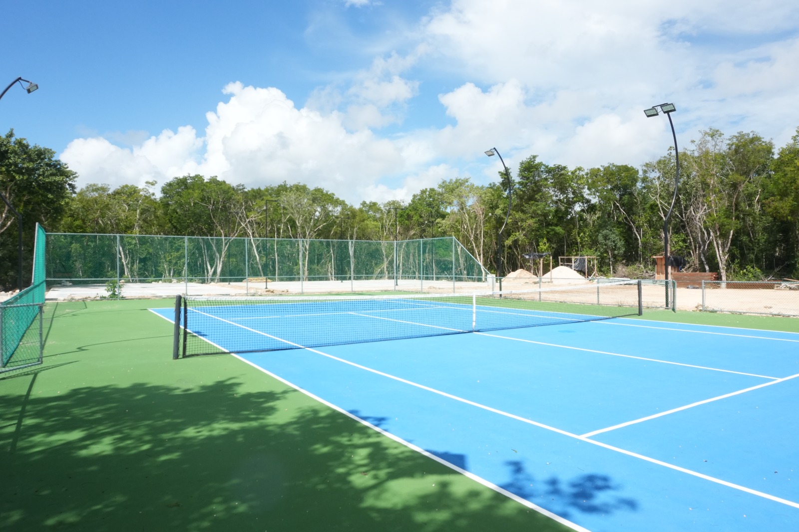 Photograph of a finished, already-built tennis court at the resort’s sports club