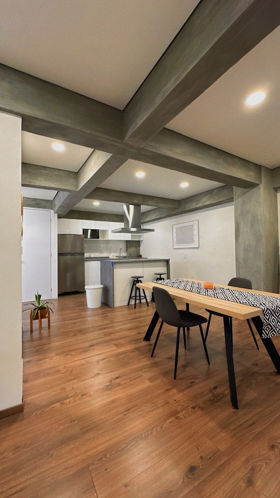 Mexico City interior with exposed concrete beams and warm wood floor